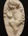 photo with black background of plaster cast relief of child dancing with a garland