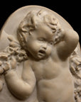 photo with black background of plaster cast relief of child dancing with a garland