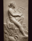 photo with black background of plaster cast sculpture relief of man, namely the god Apollo, seated on rock and playing a lyre
