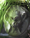 Photo of plaster sculpture of a Faun Head with dappling light and a spider plant on the left