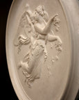 photo of plaster cast relief of female with wings flying and a cherub on her back on black background