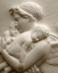 detail photo of plaster cast relief of woman with wings flying with two children nestled against her and an owl flying on a dark background