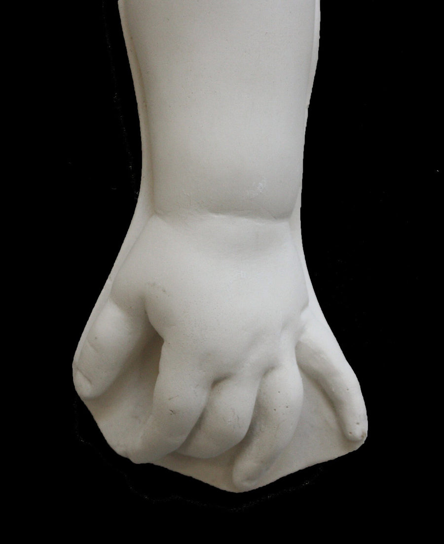 photo of white plaster cast sculpture of baby lower arm against black background