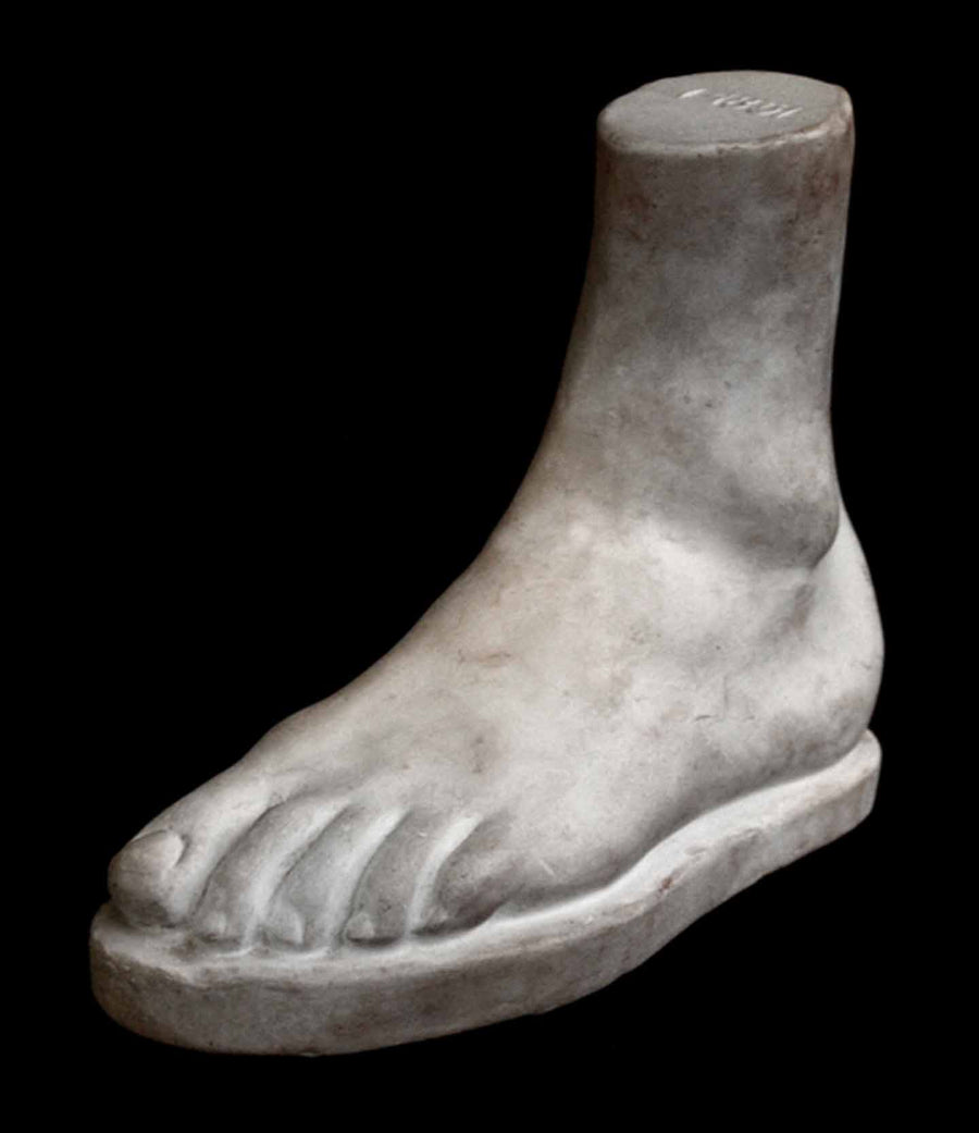 Photo of plaster cast male foot sculpture on a black background