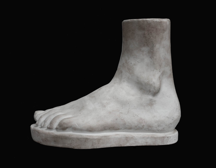 Photo of plaster cast male foot sculpture on a black background