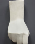 photo of white plaster cast sculpture of hand in fist in block forms against gray background