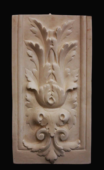 photo with a black background of plaster cast of sculpture relief with leaf ornamentation