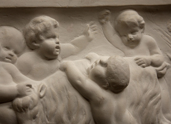 closeup photo of plaster cast relief sculpture of several putti around a goat celebrating the god Bacchus