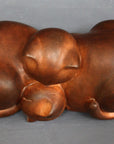 Top view photo with gray background of brown plaster cast sculpture of two cats sleeping with their heads nestled together