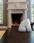 Photo of ornate living room with fireplace and columns with a plaster sculpture cast of a horse with bridal on a wooden coffee table in the foreground