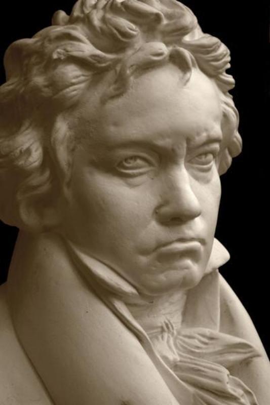 closeup photo with black background of plaster cast sculpture of male bust of Ludwig van Beethoven in dress coat and ruffled necktie