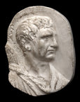 photo of plaster cast sculpture relief of male head and top of toga with a black background