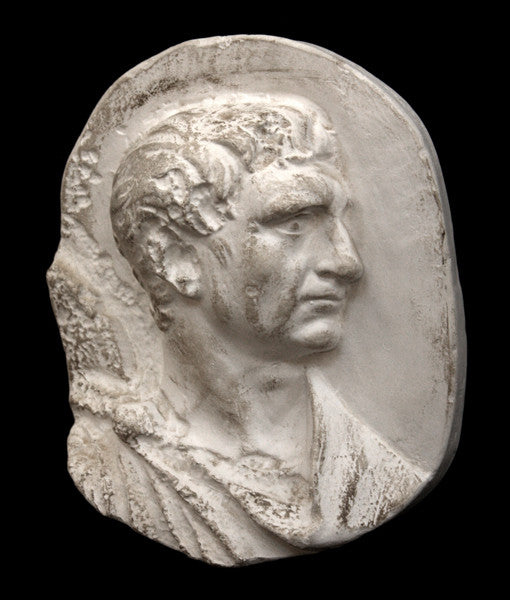 photo of plaster cast sculpture relief of male head and top of toga with a black background