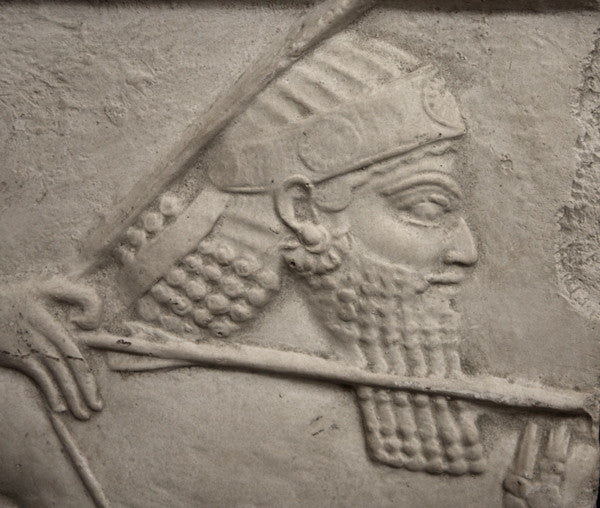 closeup photo of plaster cast relief sculpture of King Ashurbanipal on horseback and aiming an arrow in front of him