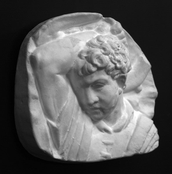 photo of plaster cast sculpture relief of upper body of male with arm raised behind head and holding a hammer with a black background