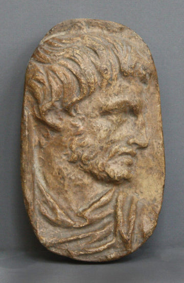 photo of plaster cast sculpture relief of male head with top of toga on a gray background