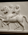 closeup photo of plaster cast relief sculpture showing two men on horses against black background