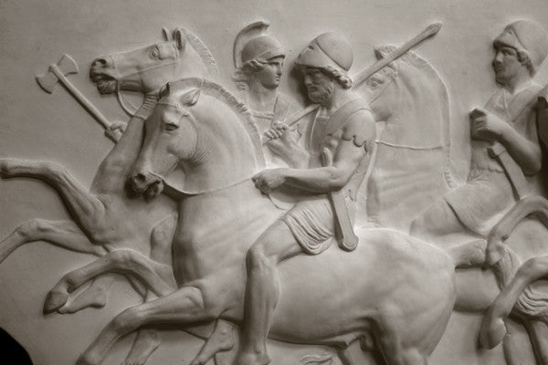 closeup photo of plaster cast relief sculpture showing three men on horses against black background
