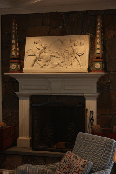 photo of plaster cast relief of men, some with armor, horses, and a dog over a fireplace with a stone wall