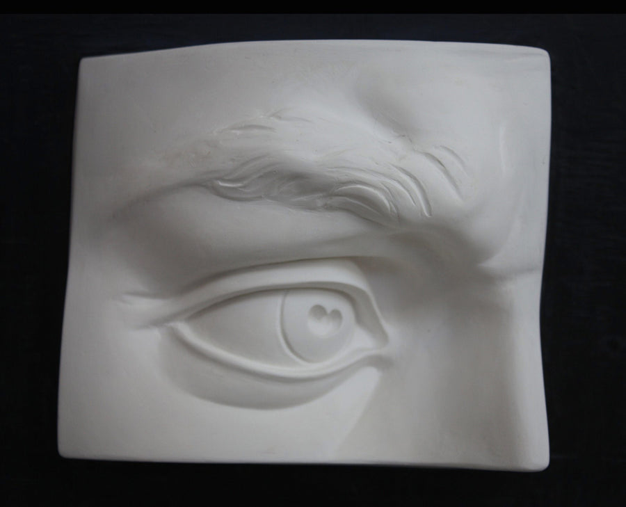 Photo of plaster cast sculpture of portion of face with right eye from Michelangelo's David statue on a black background