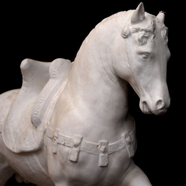 Photo of a sculpture of a plaster horse on a black background
