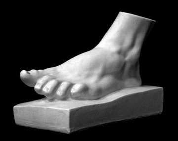 Photo of plaster cast sculpture of male foot on a thick panel at a three quarter view on a black background