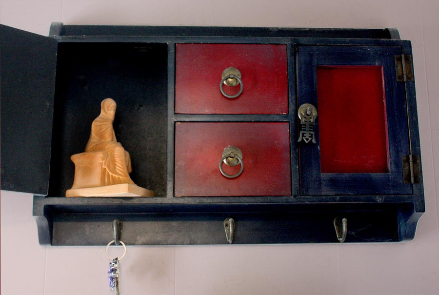 Photo of a plaster cast of a seated female figurine painted terra cotta on a small Chinese cabinet hanging on the wall