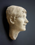 photo of antique plaster cast sculpture of front half of woman's head and neck against black background