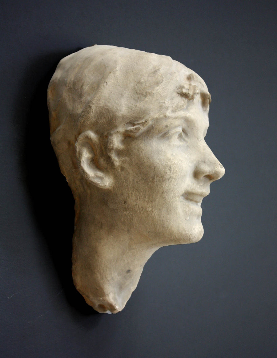 photo of antique plaster cast sculpture of front half of woman's head and neck against black background
