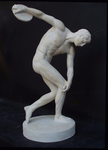 Photo with black background of plaster cast of nude male athlete readying to throw a discus