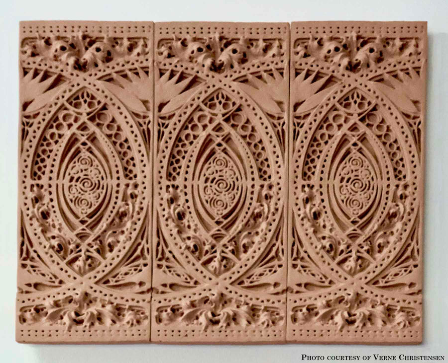 photo of plaster casts of architectural ornament with geometric lines and leaf patterns in terracotta color against white background