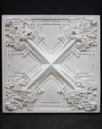 photo of white plaster cast of architectural ornament with geometric lines and leaf patterns against black background