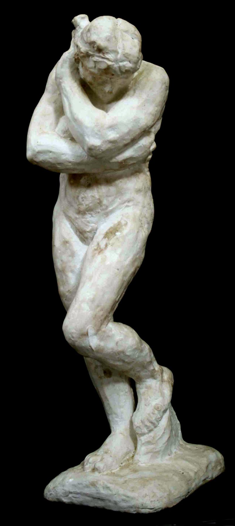 photo of antique plaster cast sculpture of nude female figure hugging herself against black background
