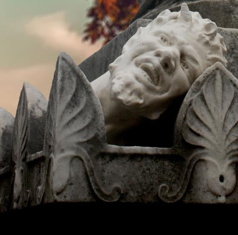 photo of satyr head atop ornamental gray stone memorial