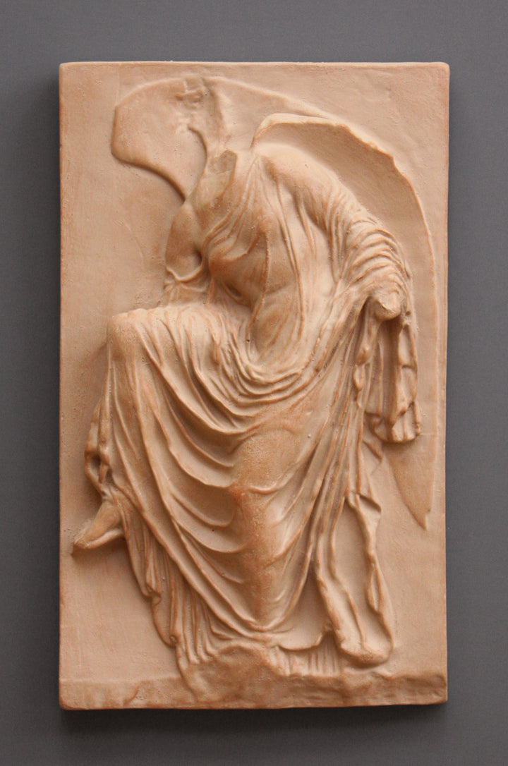 photo of cast of sculpture relief of robed figure, head now missing, reaching for her sandal in Terra Cotta Patina on a dark gray background