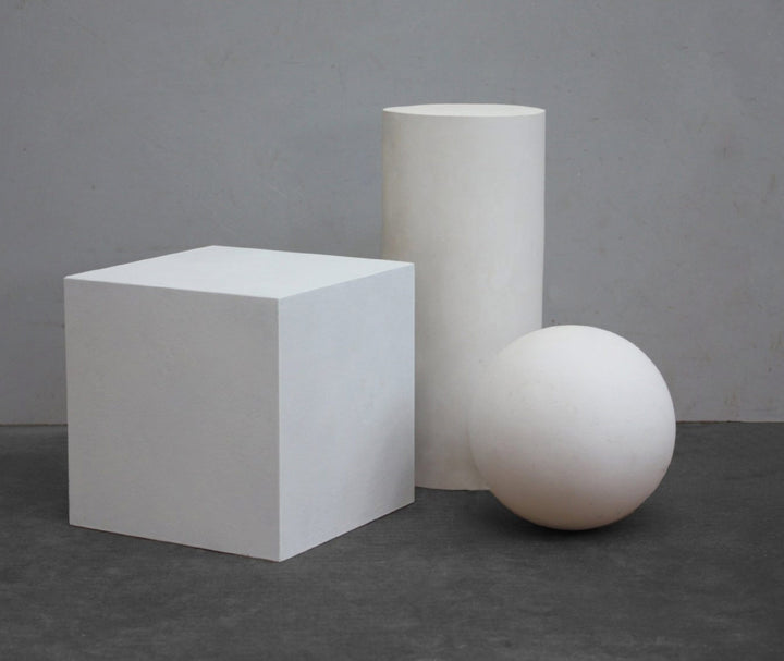 photo of plaster cube, cylinder, and sphere arranged on a gray background