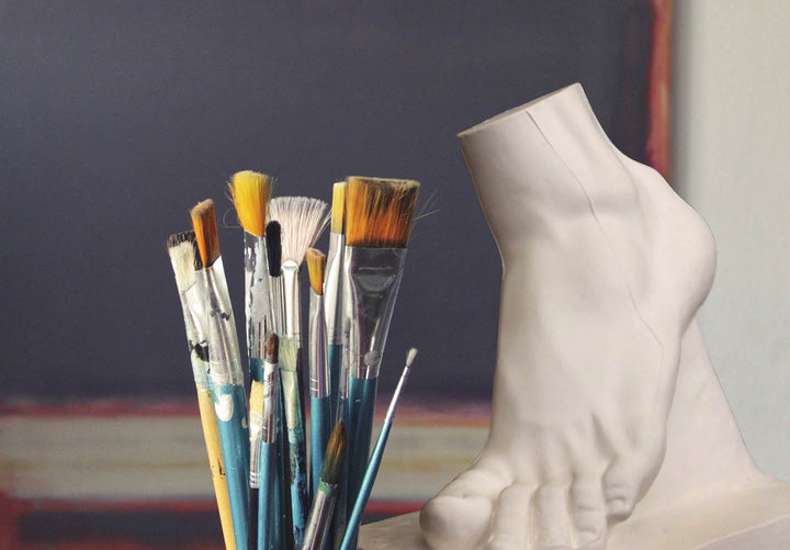 Photo of paintbrushes and plaster cast of foot in art studio