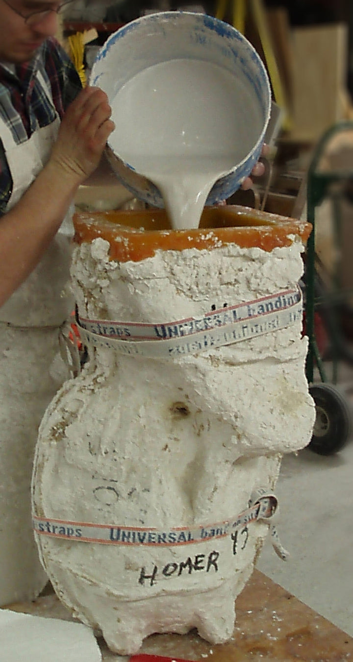 cropped photo of man pouring bucket of plaster into mold