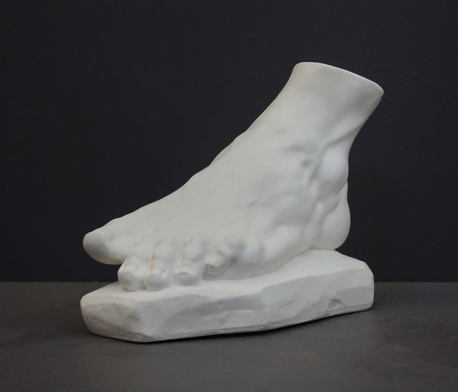 photo of white plaster cast sculpture of left foot on base against gray background