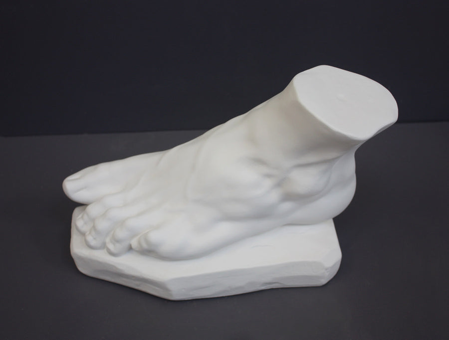 photo of white plaster cast sculpture of left foot on base against gray background