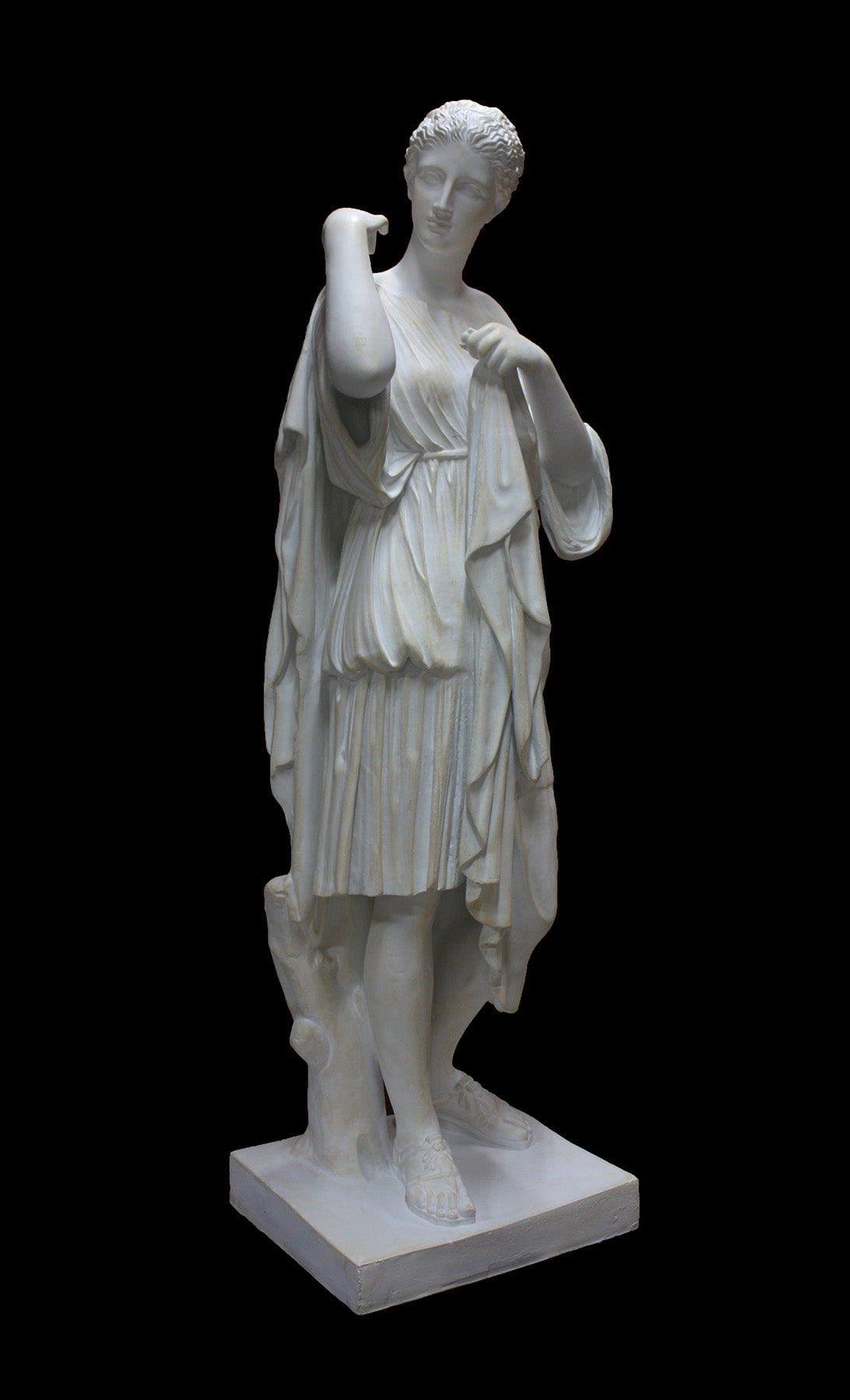 photo of white plaster cast of female figure, namely the goddess Diana, in robes about to clasp two pieces together at proper right shoulder, against black background