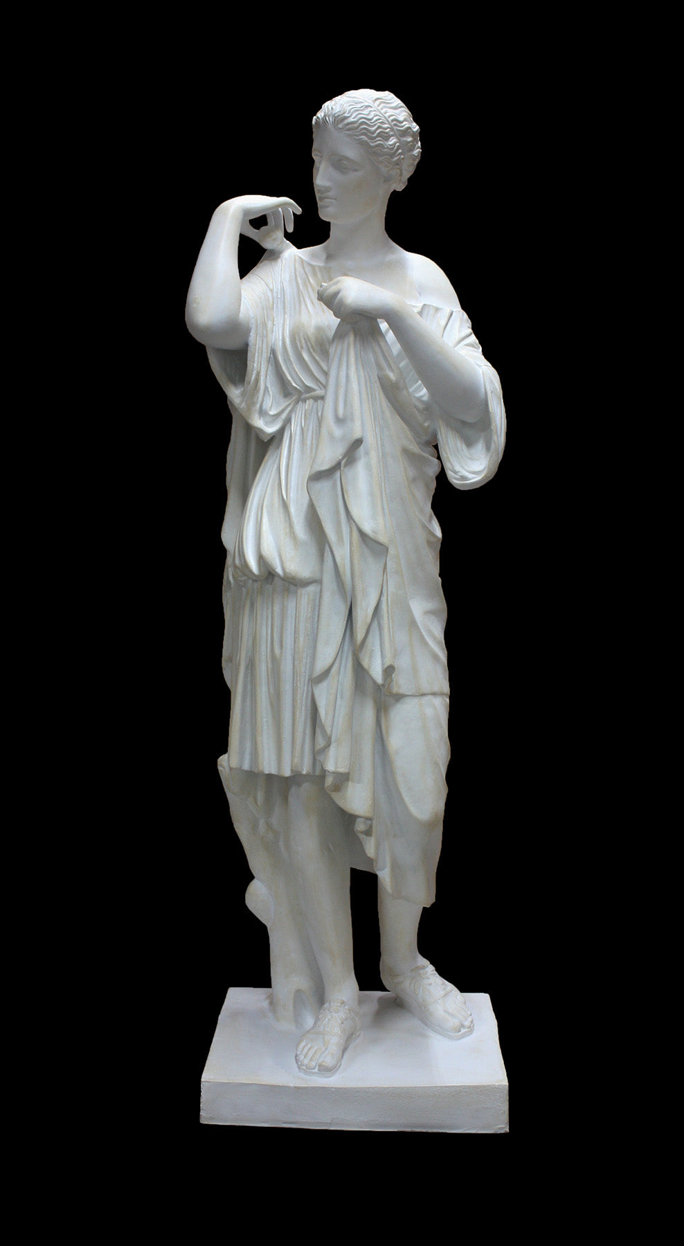 photo of white plaster cast of female figure, namely the goddess Diana, in robes about to clasp two pieces together at proper right shoulder, against black background