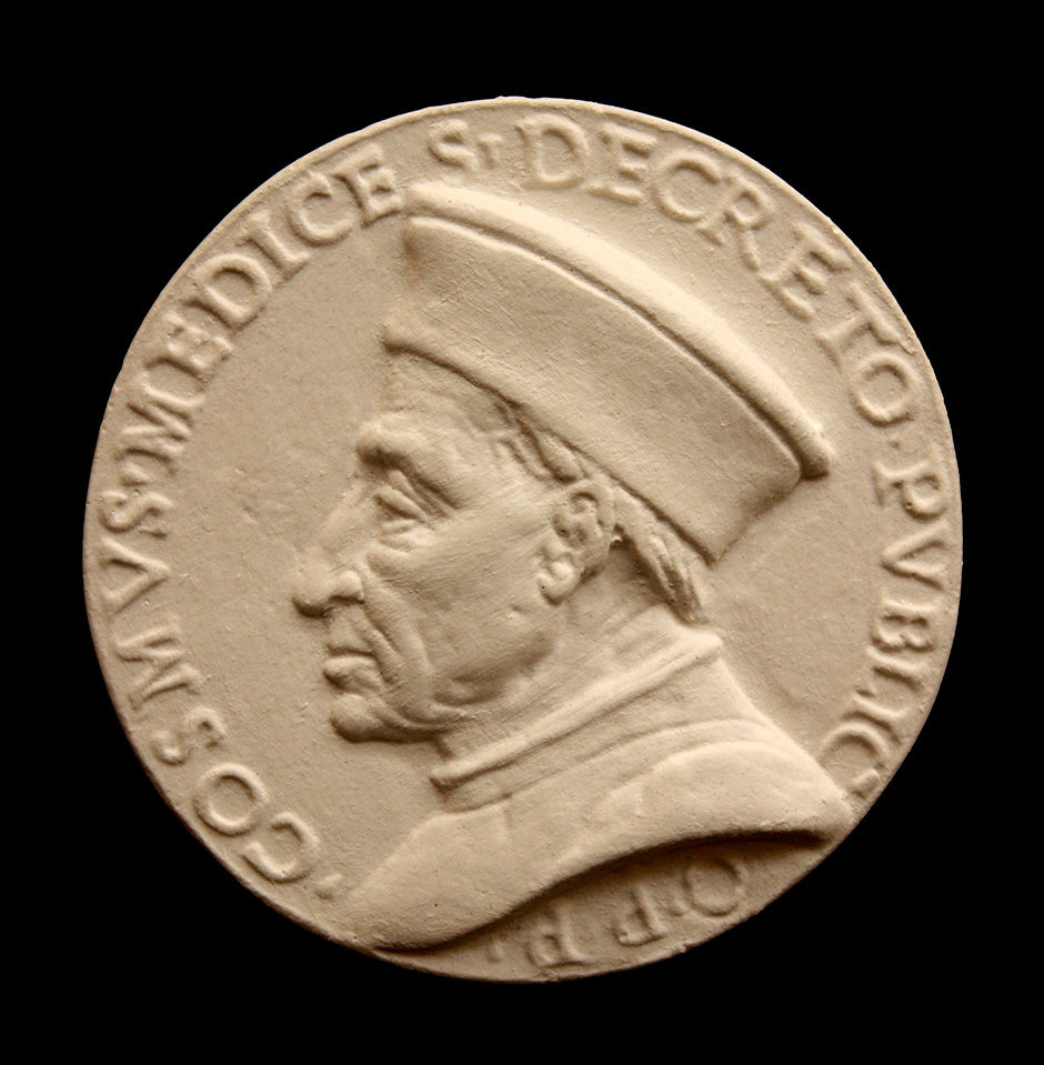 photo of off-white plaster cast relief sculpture of small medallion of male portrait in profile, namely Cosimo de Medici, and text around the edge on black background