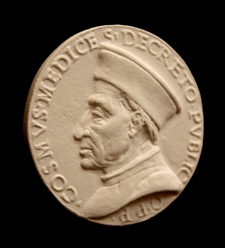 photo of off-white plaster cast relief sculpture of small medallion of male portrait in profile, namely Cosimo de Medici, and text around the edge on black background
