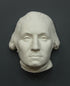 Photo of white plaster cast sculpture of mask/face of male in Revolutionary garb, namely George Washington, on gray background