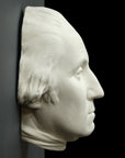 profile photo of white plaster cast sculpture of mask/face of male in Revolutionary garb, namely George Washington, on black and gray background