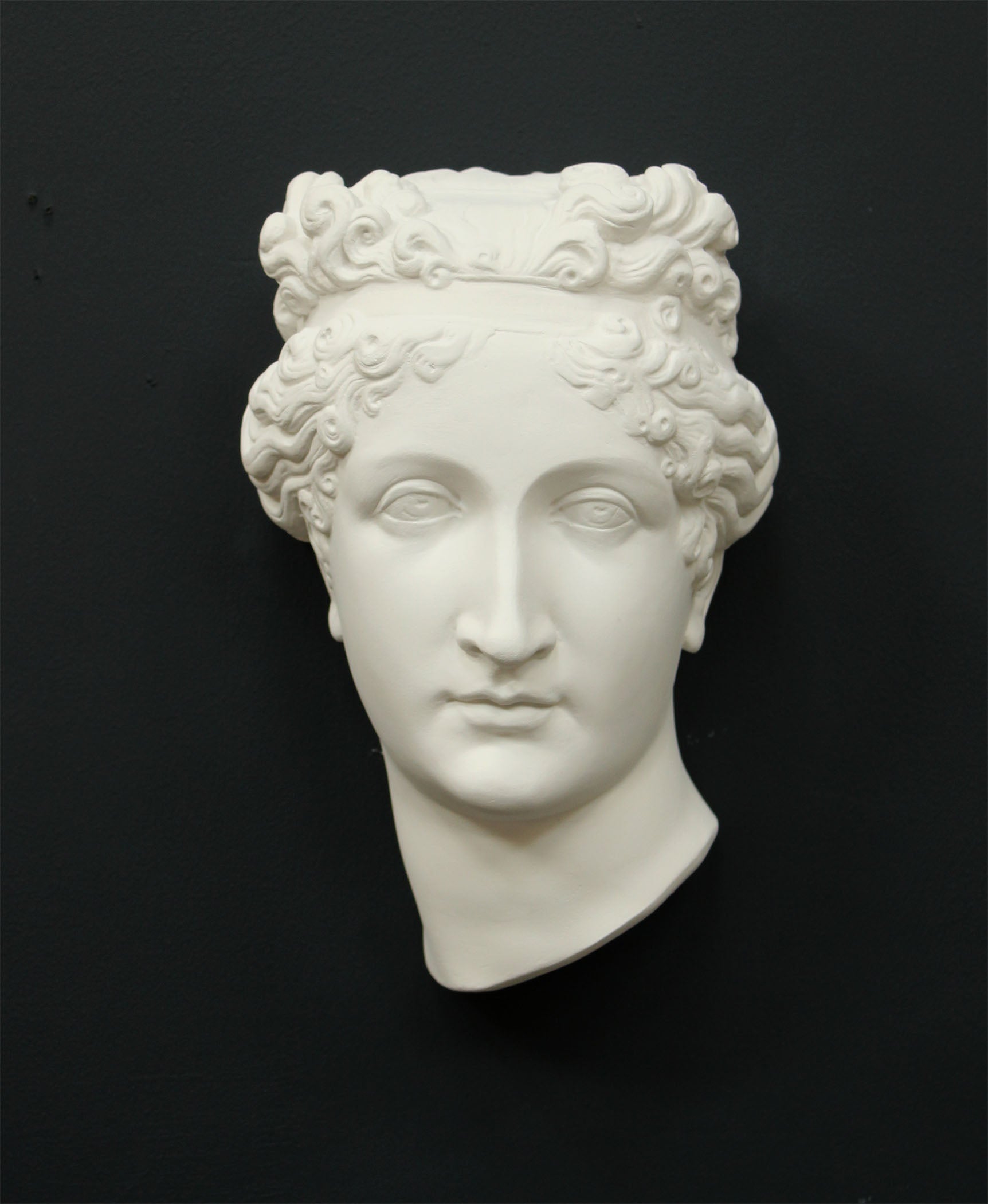 Photo of white plaster cast sculpture of mask/face of female with headband, namely Pauline Bonaparte, on gray background
