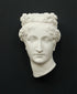 Photo of white plaster cast sculpture of mask/face of female with headband, namely Pauline Bonaparte, on gray background