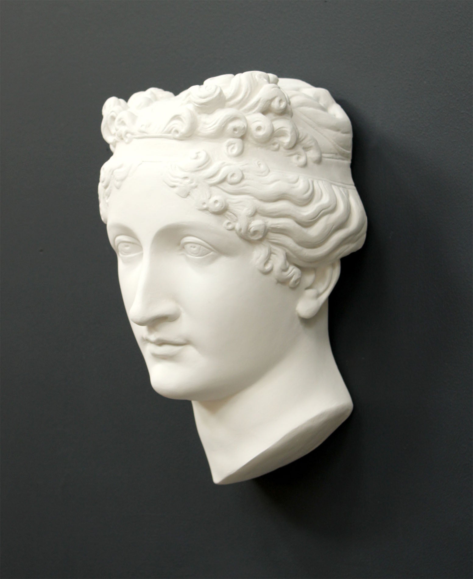 Photo of white plaster cast sculpture of mask/face of female with headband, namely Pauline Bonaparte, on gray background