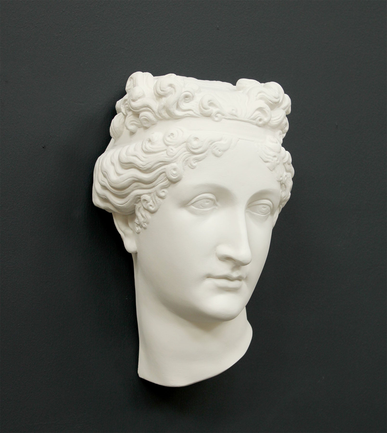 Photo of white plaster cast sculpture of mask/face of female with headband, namely Pauline Bonaparte, on gray background